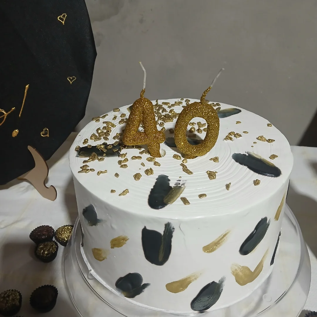Bolo branco com pinceladas douradas e velas de 40 anos